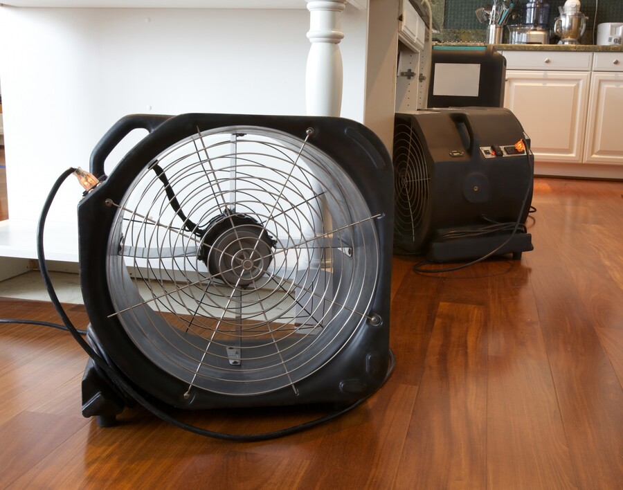 Industrial air movers on hardwood floor inside a home for water damage drying